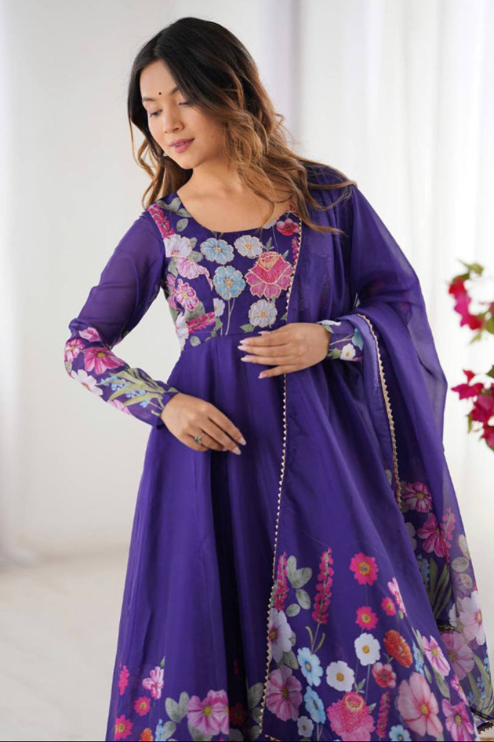 Woman wearing a purple dress with floral embroidery in a bright room.