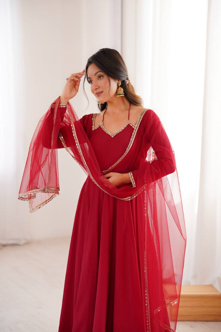 Woman wearing a red traditional outfit with a sheer dupatta against a white background