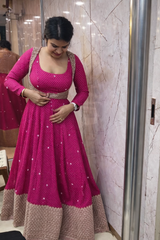 Woman wearing a pink and brown traditional outfit in front of a mirror.