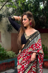 Woman wearing a red saree with gold patterns outdoors