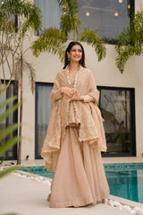 Woman in a beige traditional outfit standing by a pool with greenery around.