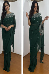 Woman wearing a green saree with silver embroidery in a room.
