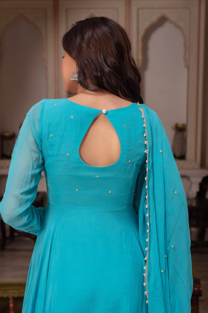 Woman wearing a turquoise traditional outfit with a backless design in an indoor setting.