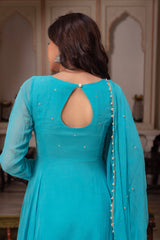 Woman wearing a turquoise traditional outfit with a backless design in an indoor setting.
