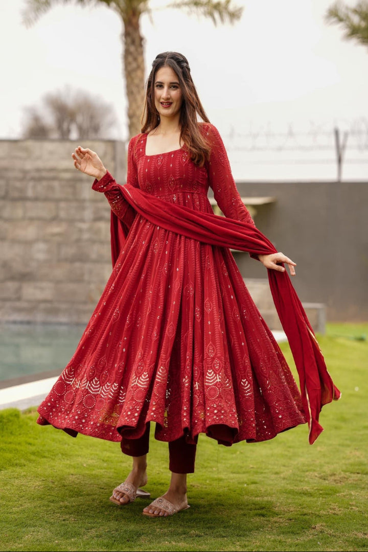 Woman in a red traditional outfit standing on grass with a blurred background