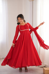 Woman in a red dress standing in a room with white curtains.