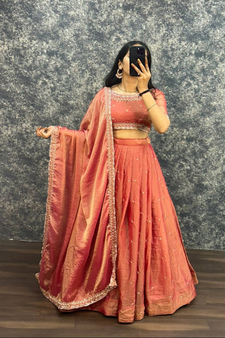Person wearing a traditional peach saree with a textured gray wall background