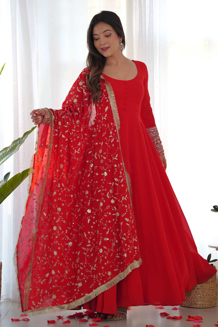Woman in a red traditional outfit with a matching dupatta, standing indoors.