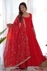 Woman in a red traditional outfit with a matching dupatta, standing indoors.