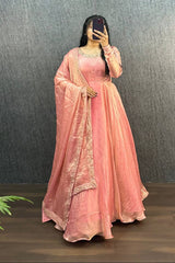 Person wearing a pink traditional outfit with a matching dupatta against a dark background.