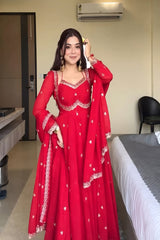 Woman in a red traditional outfit standing in a room with an air conditioner.