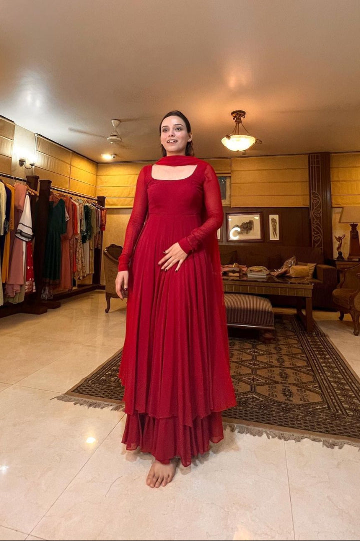 Woman in a red dress standing in a clothing store.