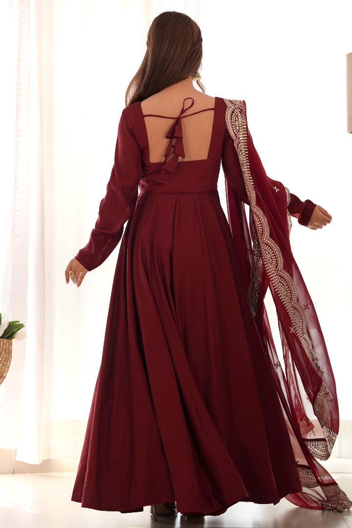 Burgundy evening gown with intricate detailing on a white background
