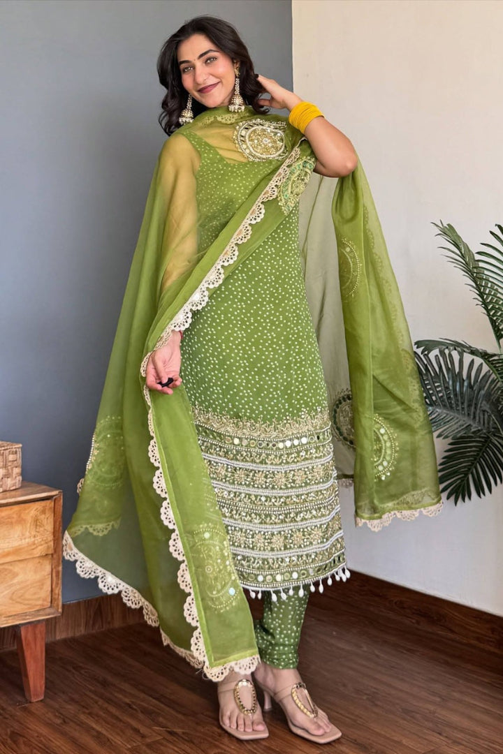 Woman wearing a green traditional outfit with a matching dupatta indoors.