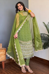 Woman wearing a green traditional outfit with a matching dupatta indoors.