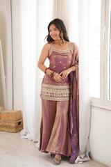 Woman in a traditional outfit standing in a bright room with white curtains.