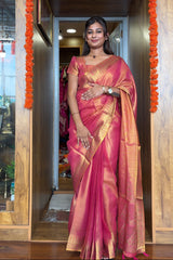 Woman in a pink saree standing in a doorway with decorative marigold flowers.