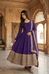 Woman in a purple traditional outfit with gold details in an ornate room.