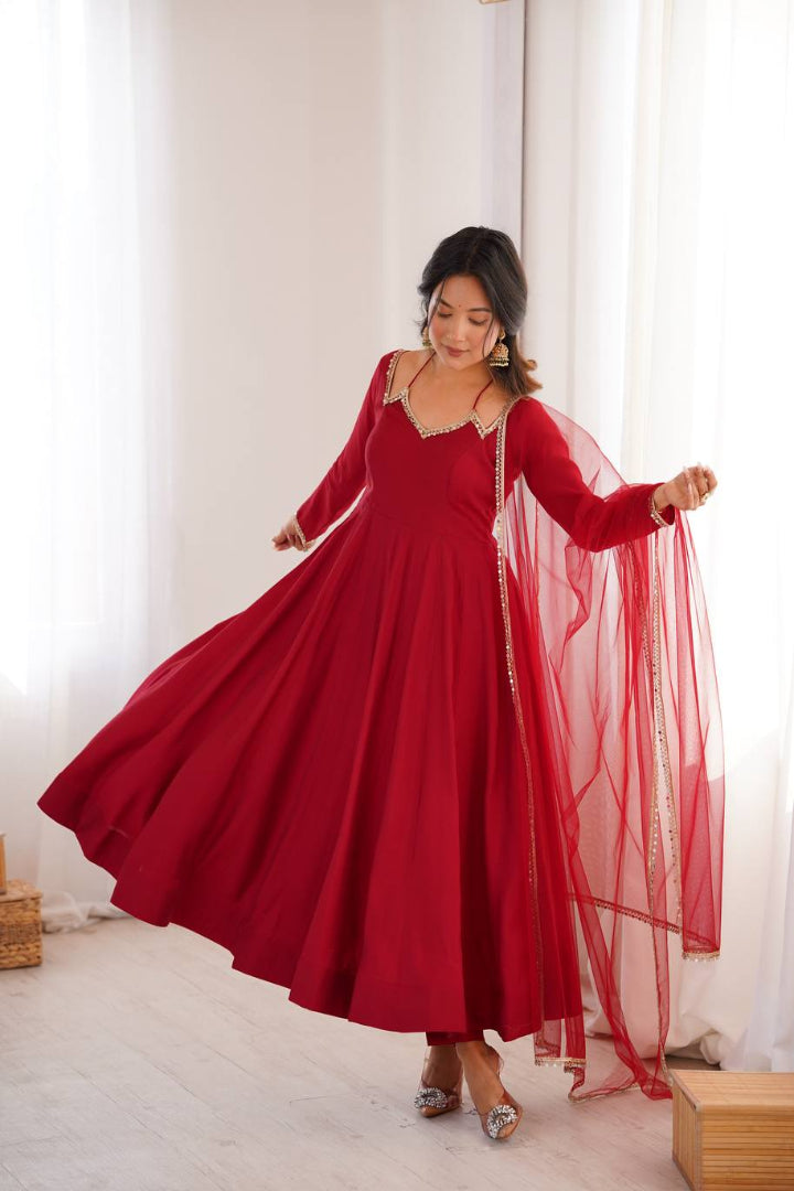 Woman wearing a red traditional outfit with a sheer dupatta in a bright room.