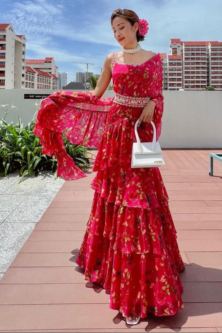 Woman in a pink floral dress standing on a rooftop with buildings in the background