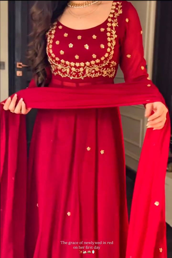 Red traditional outfit with gold embroidery held by a person.