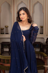 Woman in a blue traditional outfit with intricate detailing in an indoor setting.