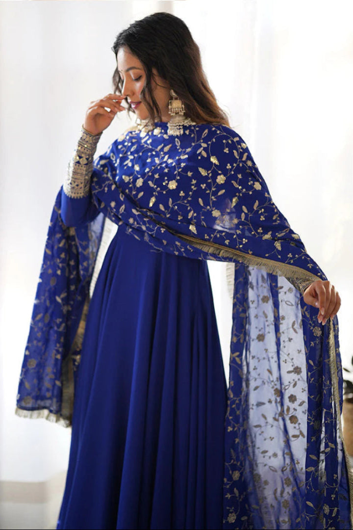 Woman wearing a blue traditional outfit with a matching dupatta in a bright room.