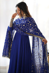 Woman wearing a blue traditional outfit with a matching dupatta in a bright room.