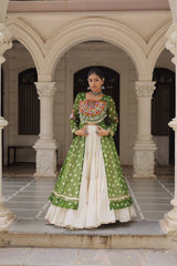 Woman in a green and white traditional outfit standing in front of an archway.