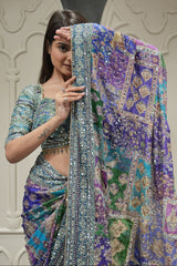 Woman wearing a colorful saree with intricate patterns, posing against a neutral background.
