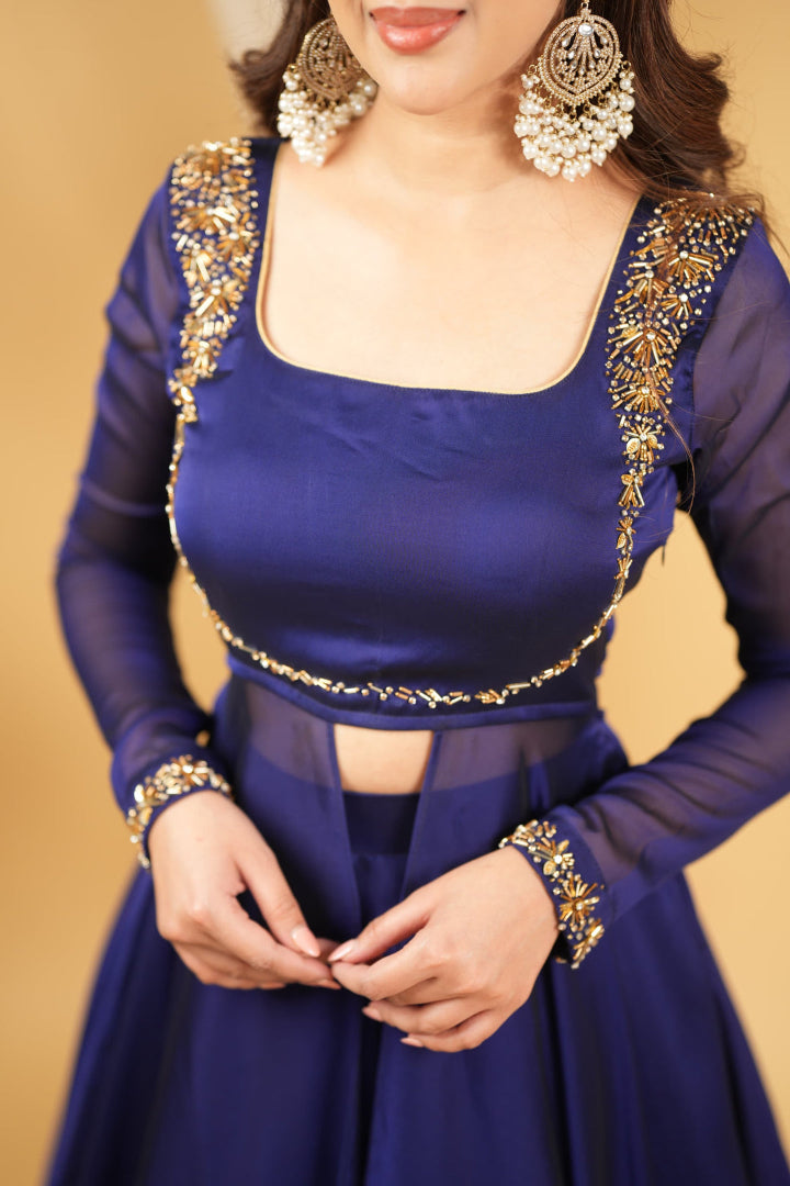 Woman wearing a blue traditional outfit with gold embroidery on a beige background
