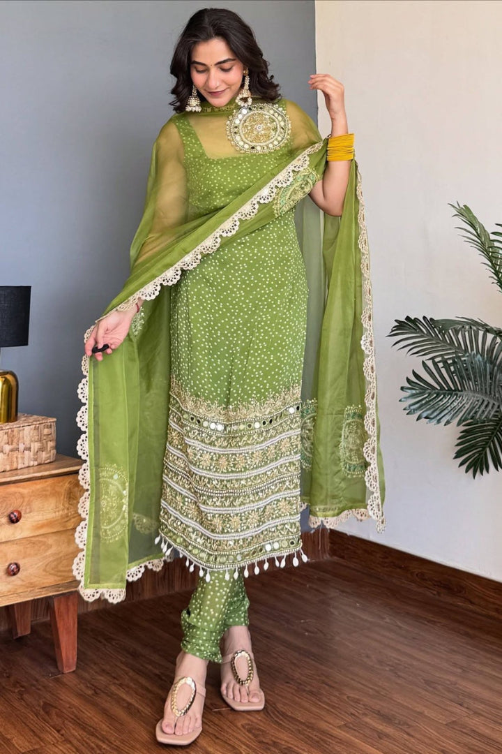 Woman wearing a green traditional outfit with a matching dupatta in a room.