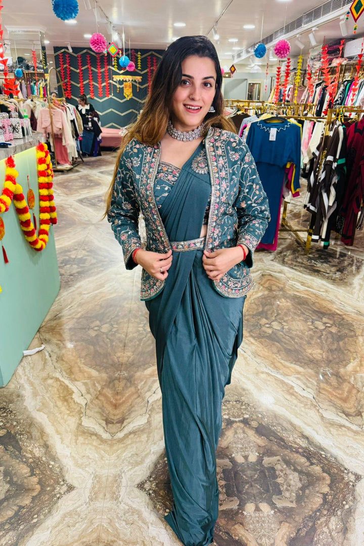Woman in a teal outfit with floral patterns standing in a store with clothing racks in the background.