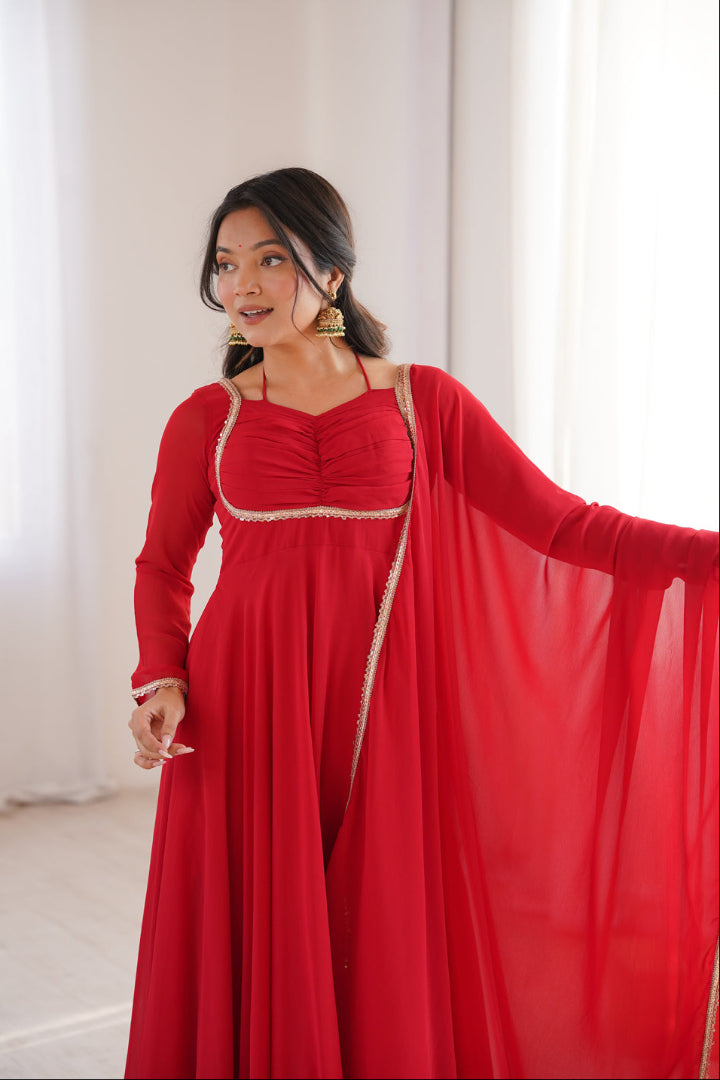 Woman wearing a red dress with a gold belt in a bright room.