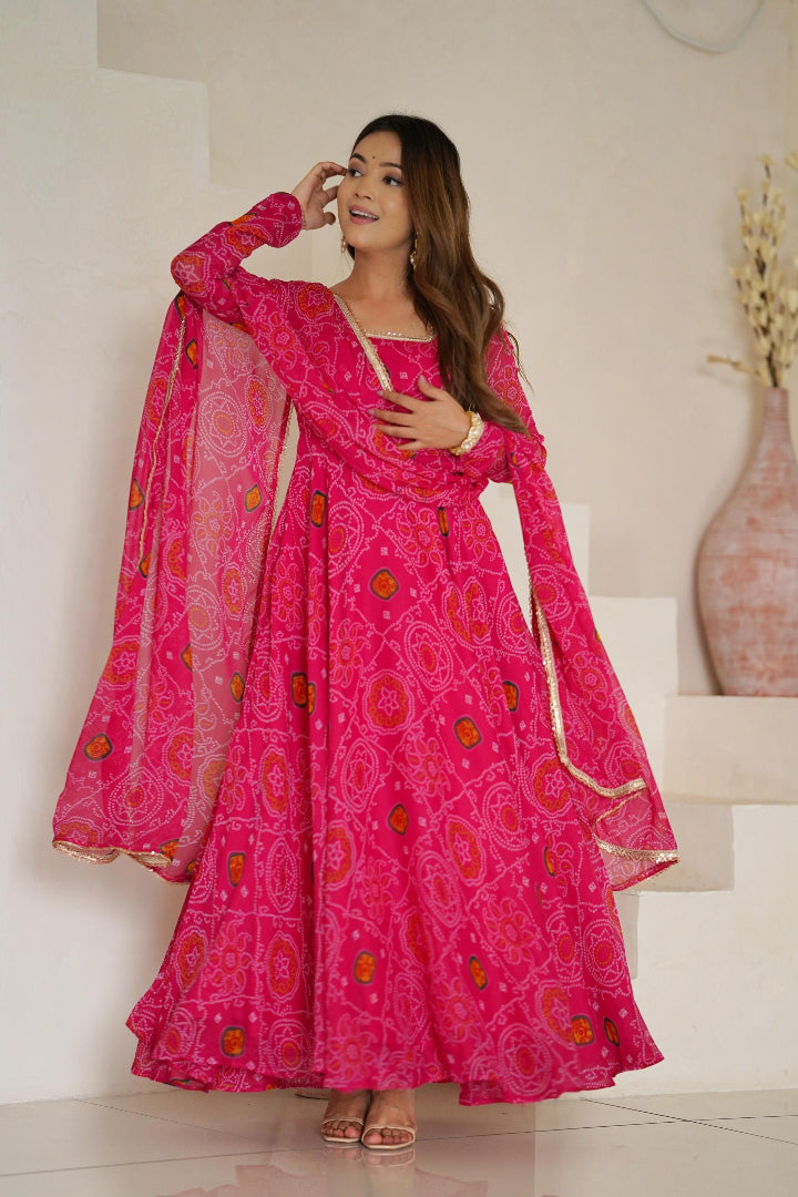 Woman wearing a pink traditional outfit with a patterned dupatta in a minimal indoor setting.