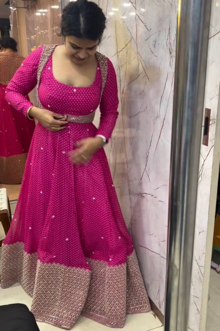 Woman wearing a pink and brown traditional outfit in front of a mirror.