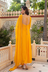 Woman in a yellow dress standing on a decorative balcony with greenery in the background