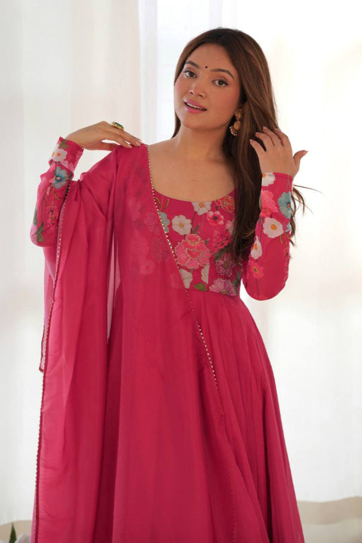 Woman wearing a pink embroidered dress with a white background