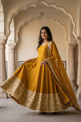 Woman in a yellow traditional outfit with gold details standing in an ornate architectural setting.