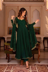 Woman in a green traditional outfit standing in an ornate room.