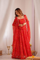 Woman in a red traditional outfit with a patterned dupatta against a white curtain background
