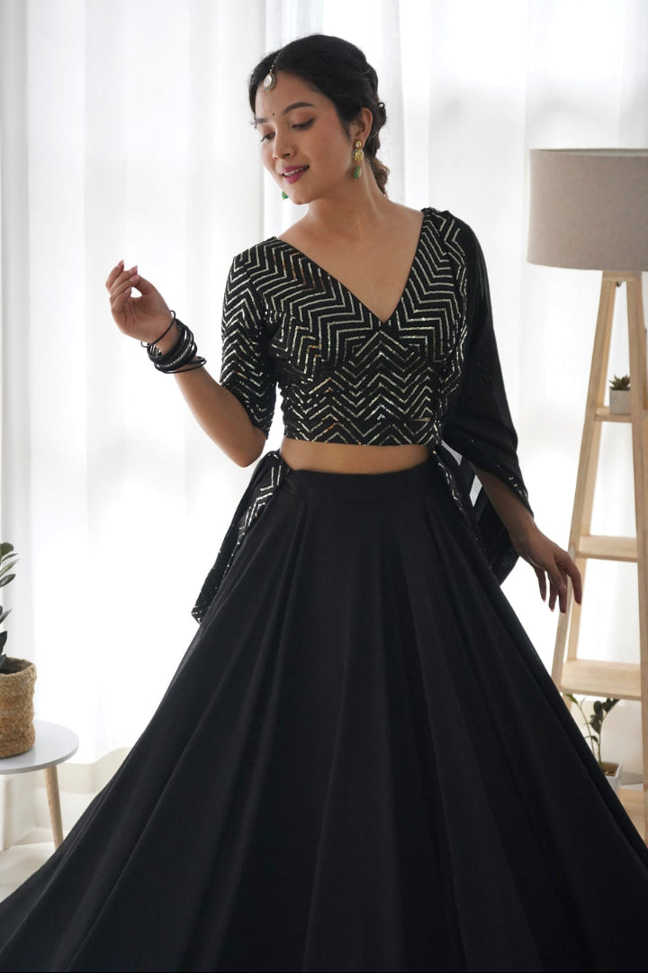 Woman wearing a black and white patterned top with a long black skirt in a bright room.