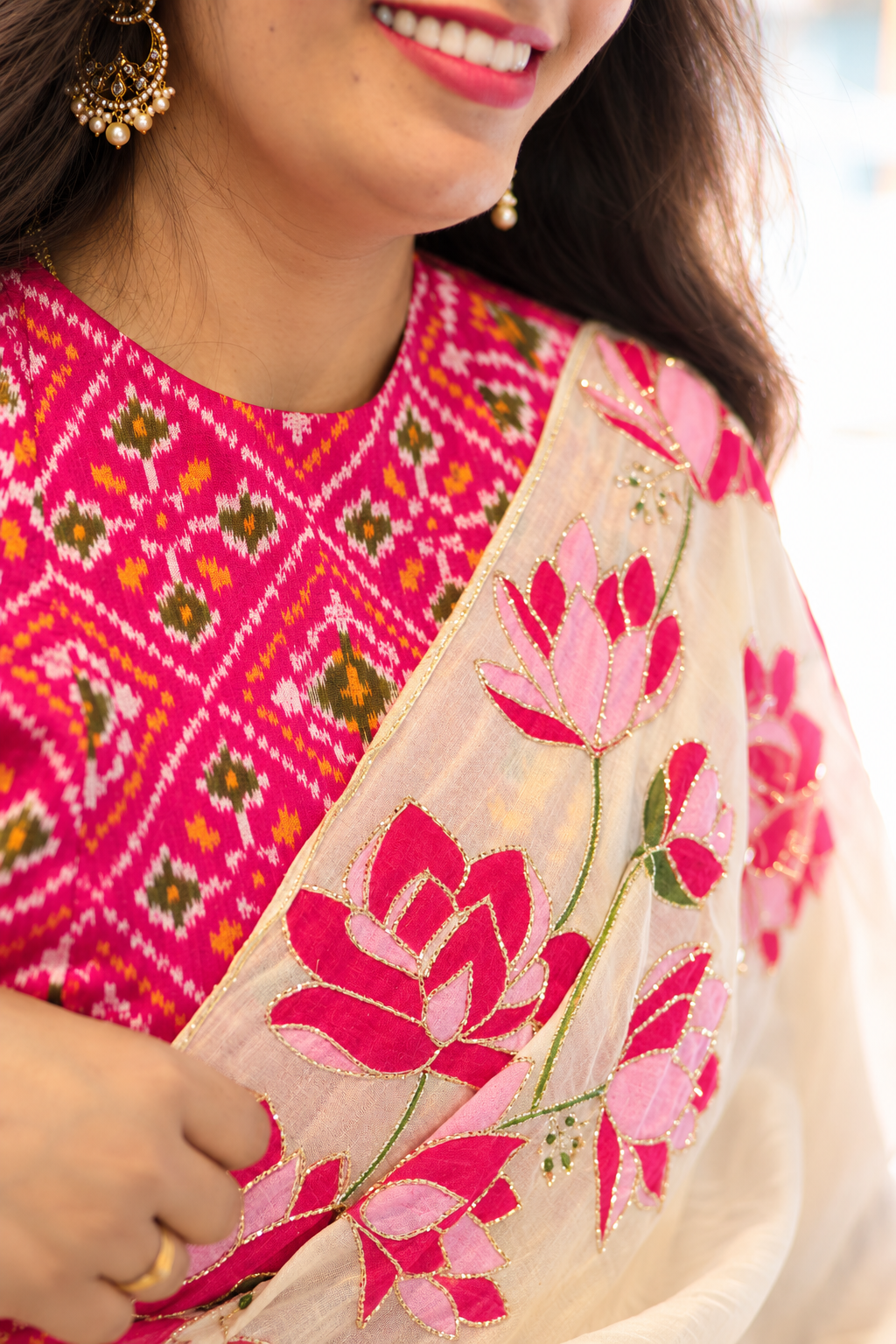 Close-up of a woman wearing a bright pink embroidered traditional outfit with a matching sheer beige dupatta featuring large pink floral embroidery.