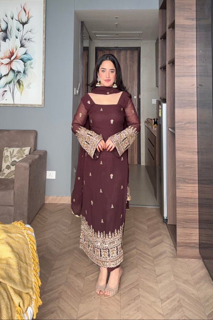 Woman in a dark purple traditional outfit standing in a modern living room.