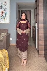 Woman in a dark purple traditional outfit standing in a modern living room.
