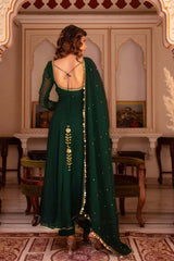 Woman in a green traditional outfit with gold details in an ornate room.