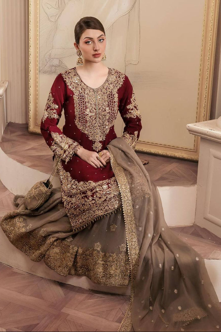 Woman in a maroon and gold embroidered traditional outfit sitting on a staircase.
