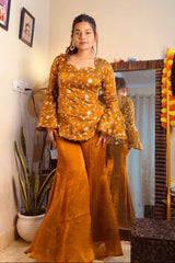 Woman in a mustard yellow outfit standing in front of a mirror.