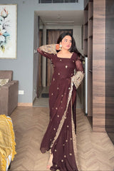 Woman in a maroon saree with gold details standing in a room.