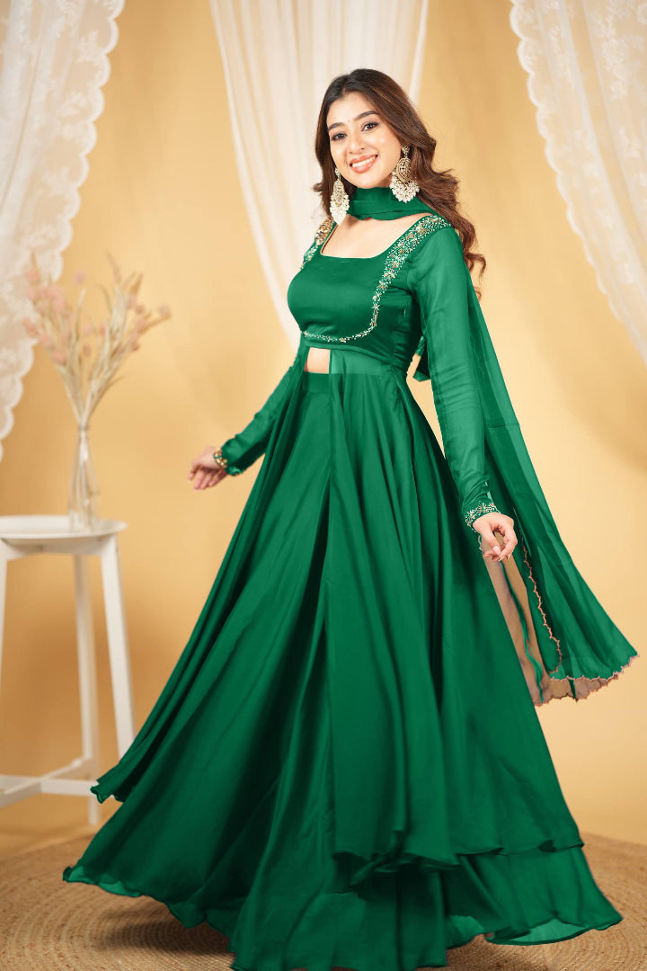 Woman wearing a green dress with intricate detailing against a beige curtain background